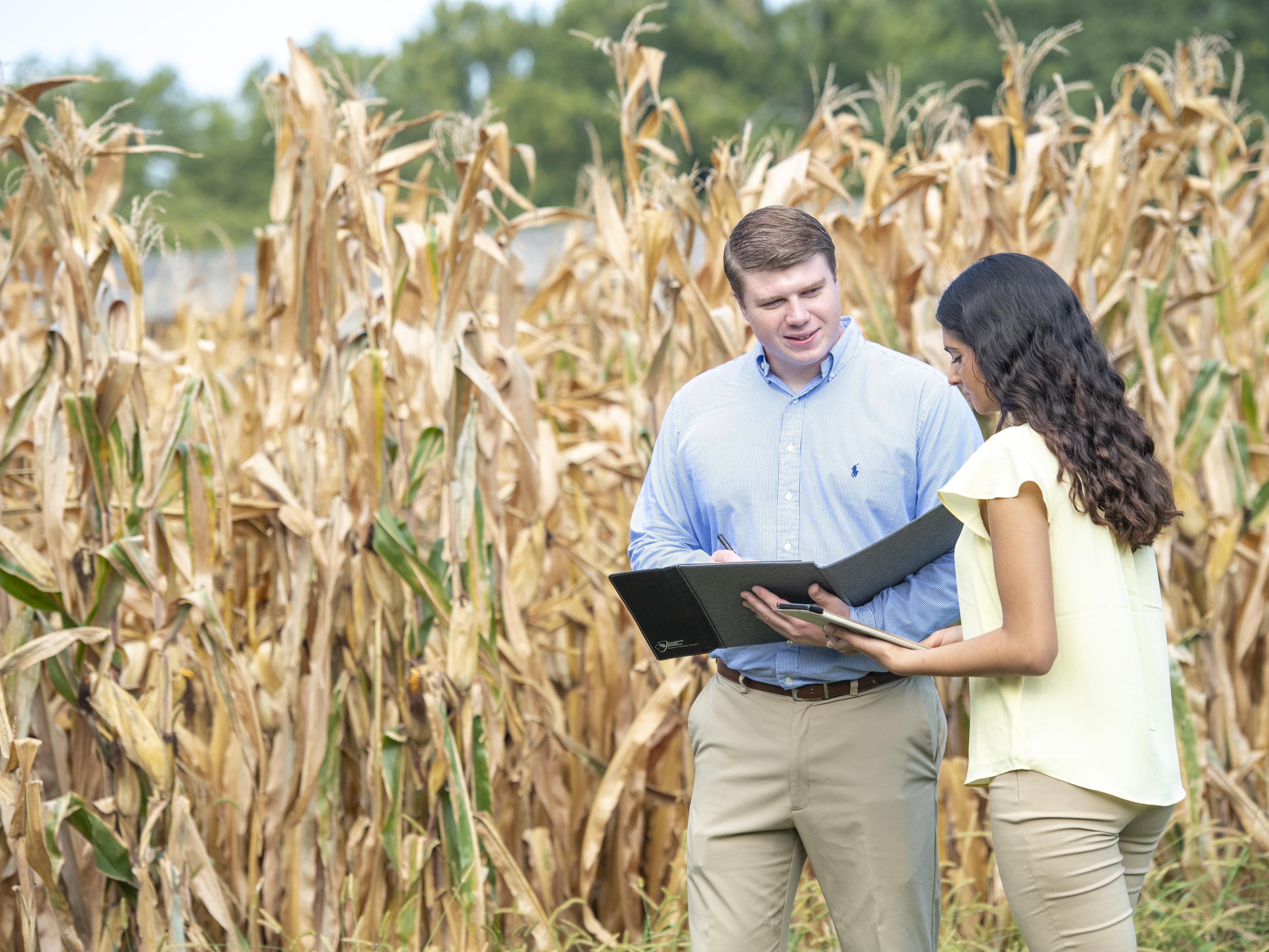 Two people talking next to a field.