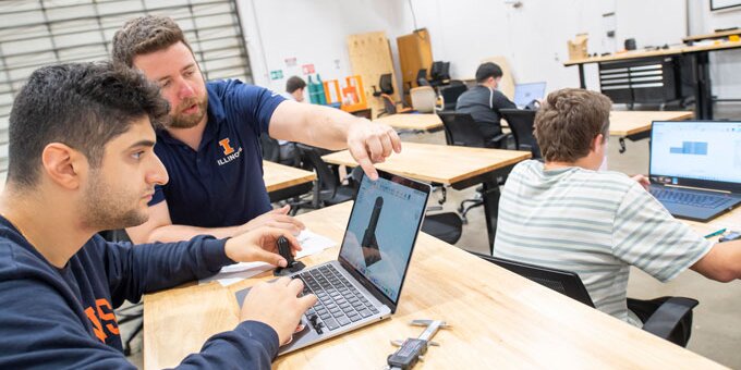 Instructor assisting a student working on a laptop
