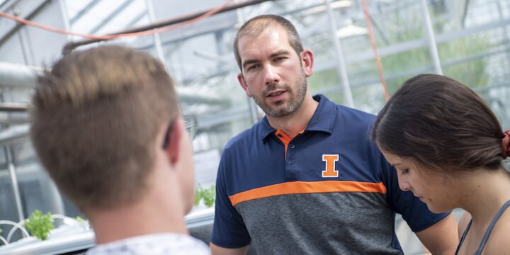 Professor conversing with students in greenhouse